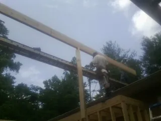 Carpenter setting a ridge beam over a new addition frame — Ice Dam Removal by Roofing Brothers in Manville