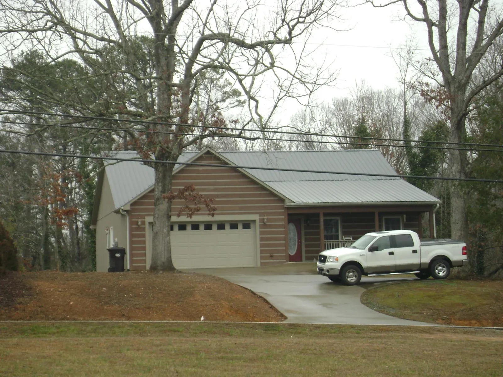 Gray metal roof on a log sided house with an attached two car garage in Manville