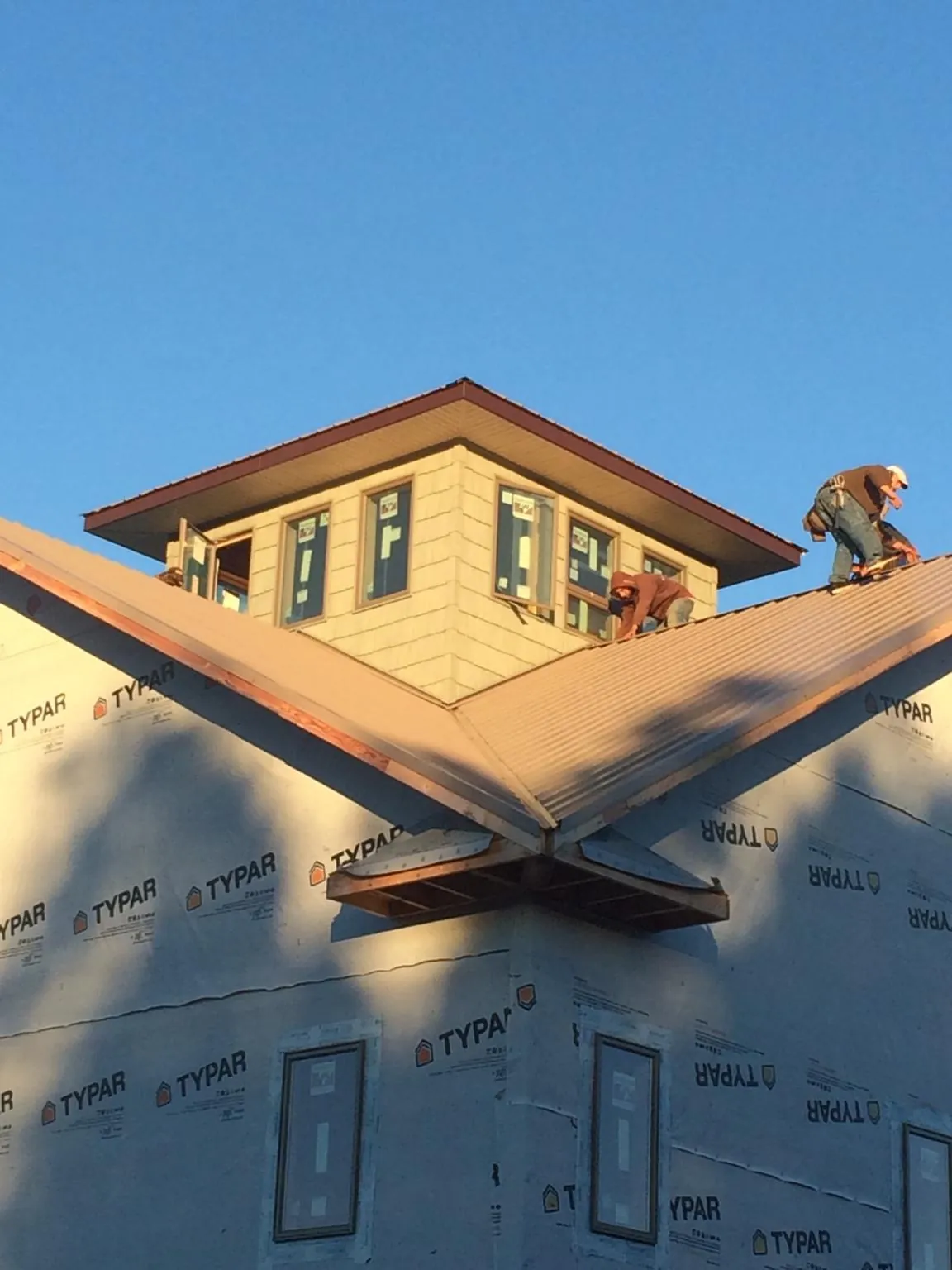 Roofers working around a rooftop cupola on a new metal roof at sunset — Roof Waterproofing in Manville by Roofing Brothers
